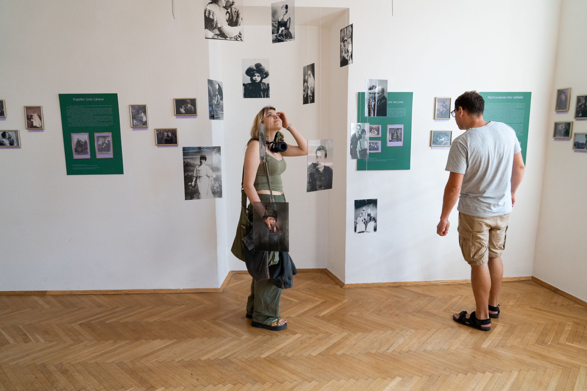 Kobieta i mężczyzna oglądają wystawę fotografii w sali wystawowej.