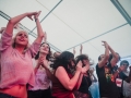 [Zdjęcie przedstawia roztańczonych i rozśpiewanych ludzi z publiczności podczas koncertu pod namiotem.]